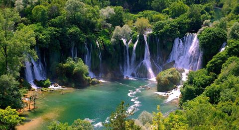 The wide Kravica waterfalls fanning into a turquoise pool surrounded by greenery