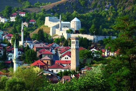 Ottoman-era houses and minarets in the old town of Travnik beneath green hills