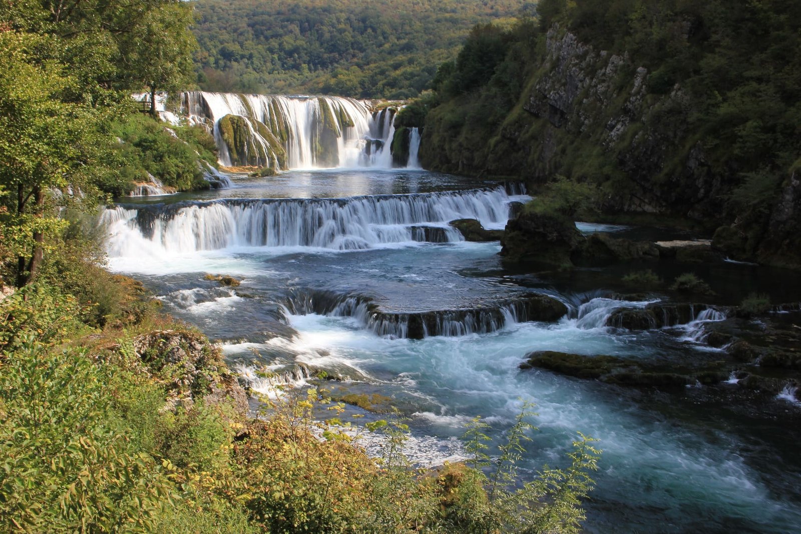 The Una river tumbling over the wide cascades of Štrbački buk between green forested banks